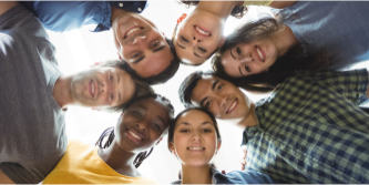 Fotografía de personas jóvenes sonrientes en círculo con las cabezas juntas sonriendo.